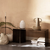 Stylish black and transparent console table with soft white and beige accents, surrounded by earthy textures.