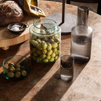 "Elegant glass containers in green and gray hues, featuring unique textures and patterns, perfect for stylish dining."
