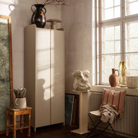 Minimalist beige cabinet against a soft, muted wall, complemented by earthy tones and natural textures.