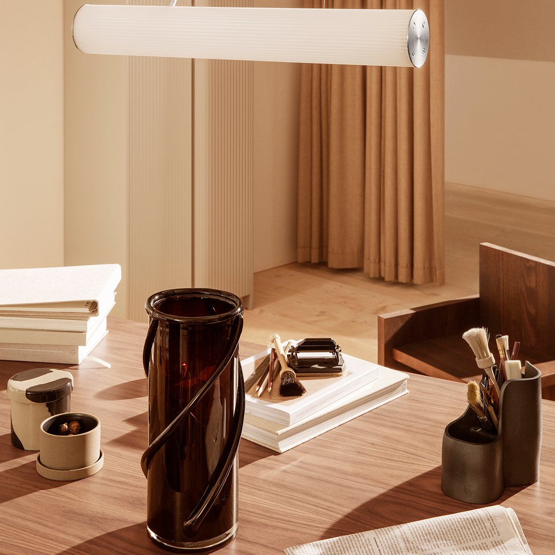 "Amber vase with a spiral pattern on a warm-toned wooden desk, surrounded by neutral-colored decor."