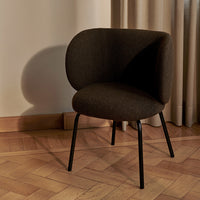 Brown upholstered chair with smooth curves and black metal legs, set against a light wooden floor.