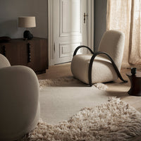 Cozy interior featuring soft beige armchairs, a textured cream rug, and warm brown wood accents.