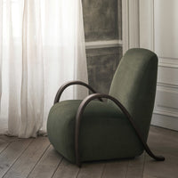 Green upholstered chair with smooth curves and dark wood accents, set against a light, neutral background.
