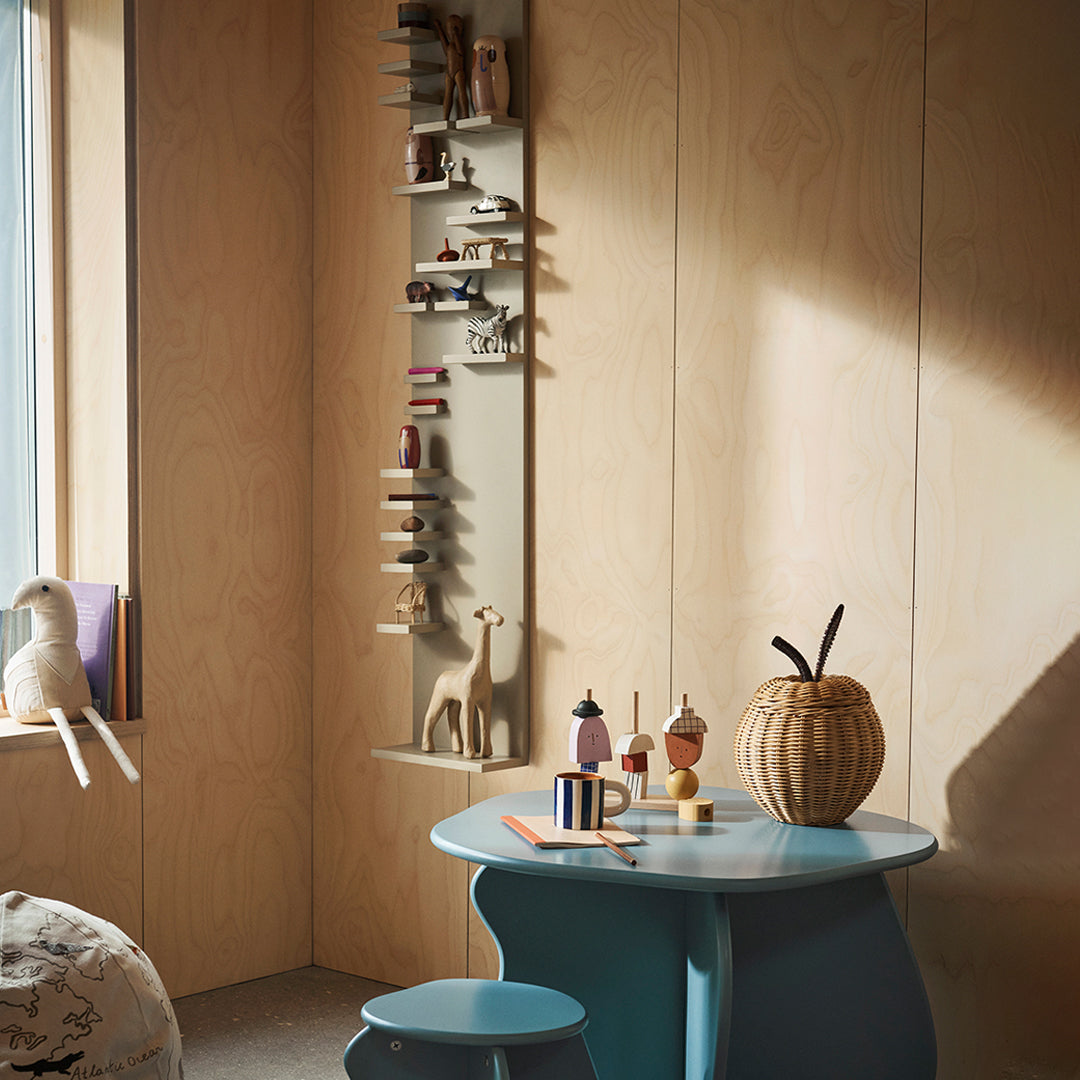 Mint green table and stool against warm wood walls, featuring colorful decor and playful patterns in a cozy setting.
