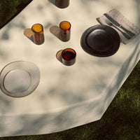 "Stylish glassware in amber and black shades on a neutral table setting with soft shadows."