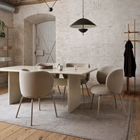 Beige upholstered dining chairs around a minimalist beige table on a soft gray rug with wood flooring.
