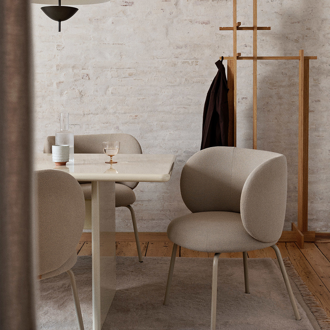 Soft beige chairs with rounded backs, set against a light neutral-toned wall and wooden accents in a modern dining space.