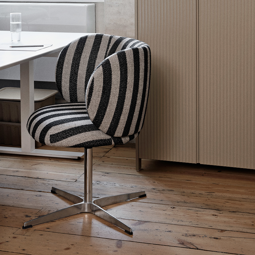 Black and white striped fabric chair with a sleek metal base, set against a neutral-colored wooden floor.