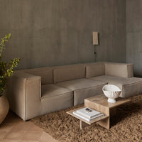 Beige modern sofa with minimalist design and neutral color palette, complemented by a textured brown rug.