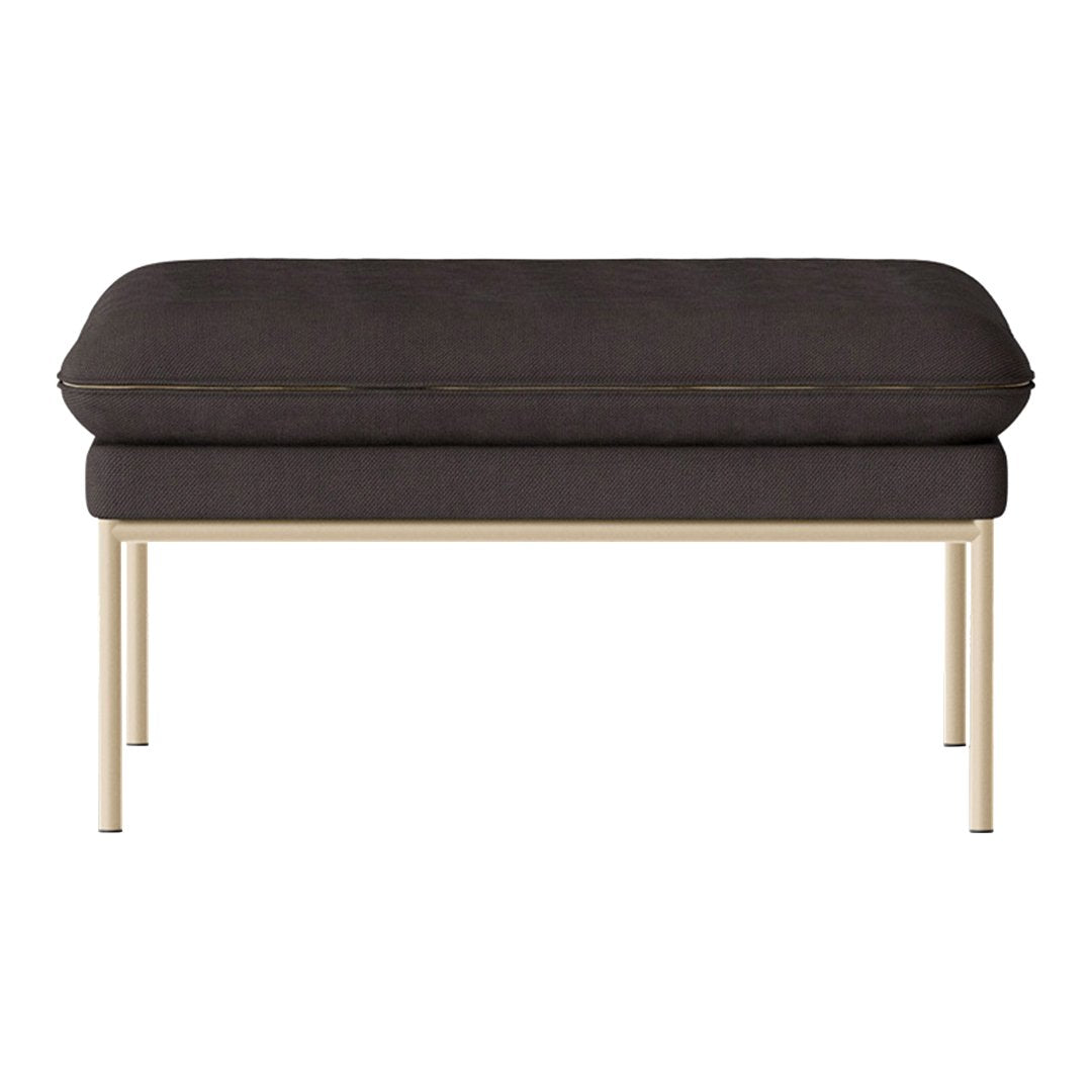 Dark gray upholstered ottoman with gold metal legs, featuring a sleek and modern design.