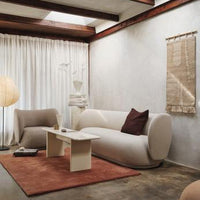Light gray walls, warm terracotta rug, soft beige furniture with a burgundy accent pillow for a modern, cozy vibe.
