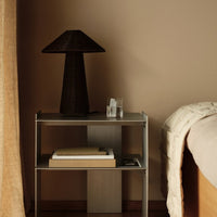 Stylish black lamp atop a sleek silver nightstand with neutral beige tones and a soft textured blanket.