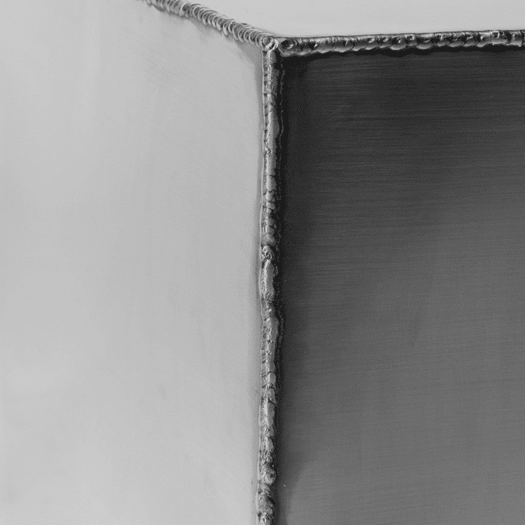Close-up of a textured metallic surface in shades of grey with subtle reflections and precise welding patterns.