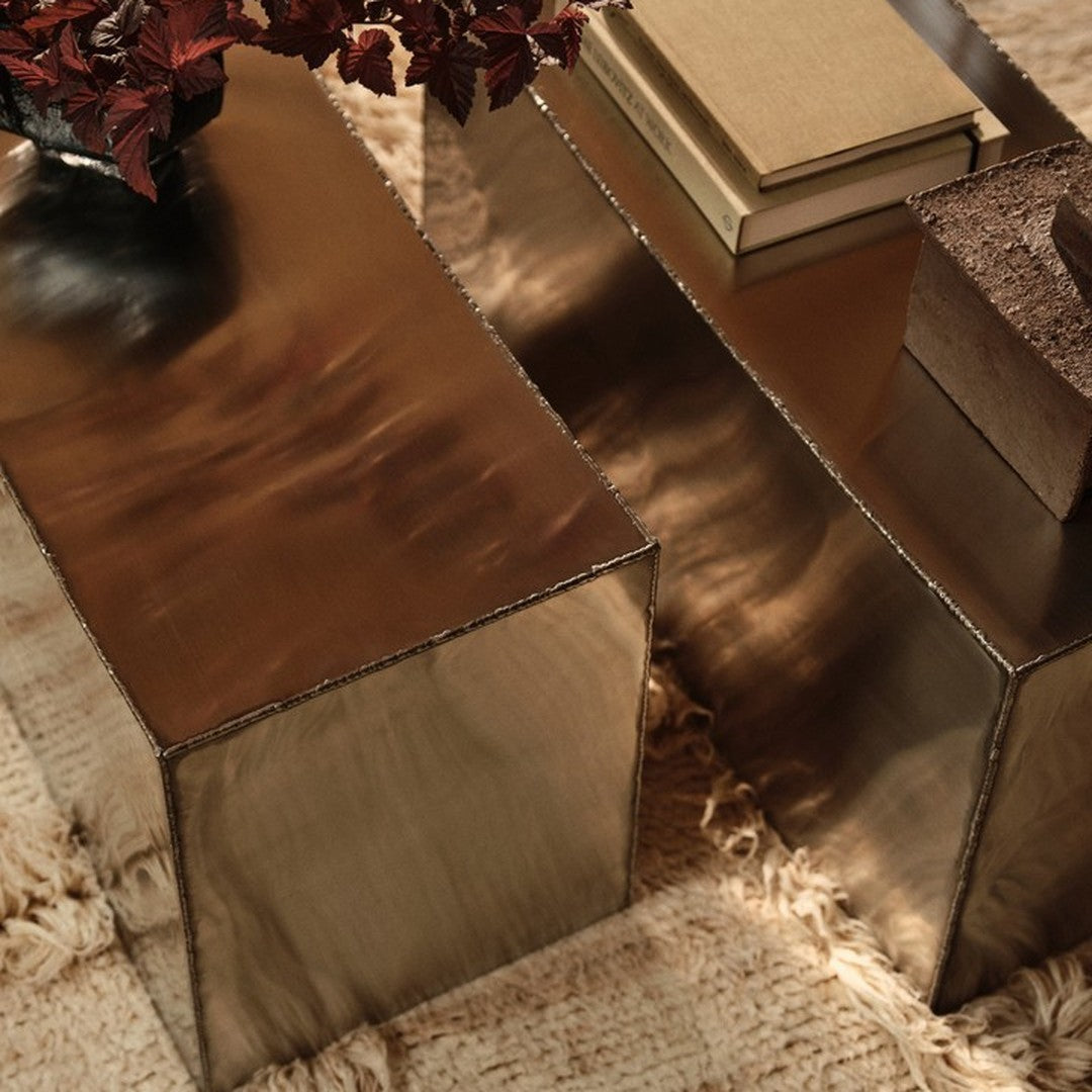 Metallic copper coffee tables with sleek reflective surfaces, complemented by warm beige and rich brown accents.