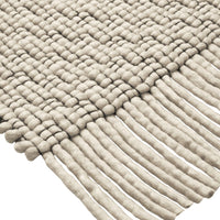 Textured beige woven rug with unique patterns and fringed edges, perfect for adding warmth to any space.