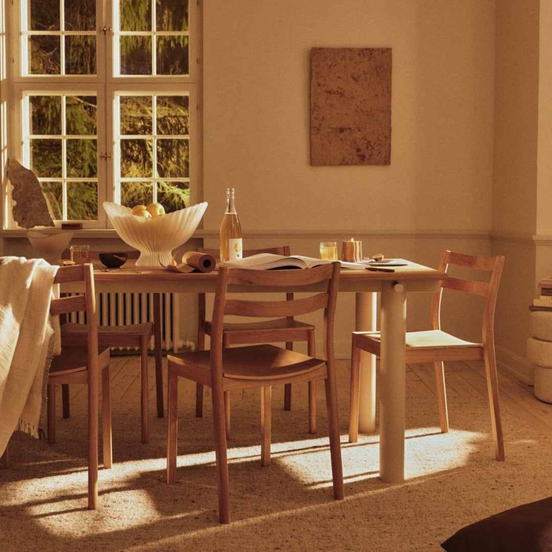 "Light wood dining table with beige and warm tones; complemented by wooden chairs and textured walls for a cozy vibe."