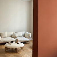 Cozy living room with beige sofa, light wood floor, and soft coral wall accent, creating a warm and inviting atmosphere.