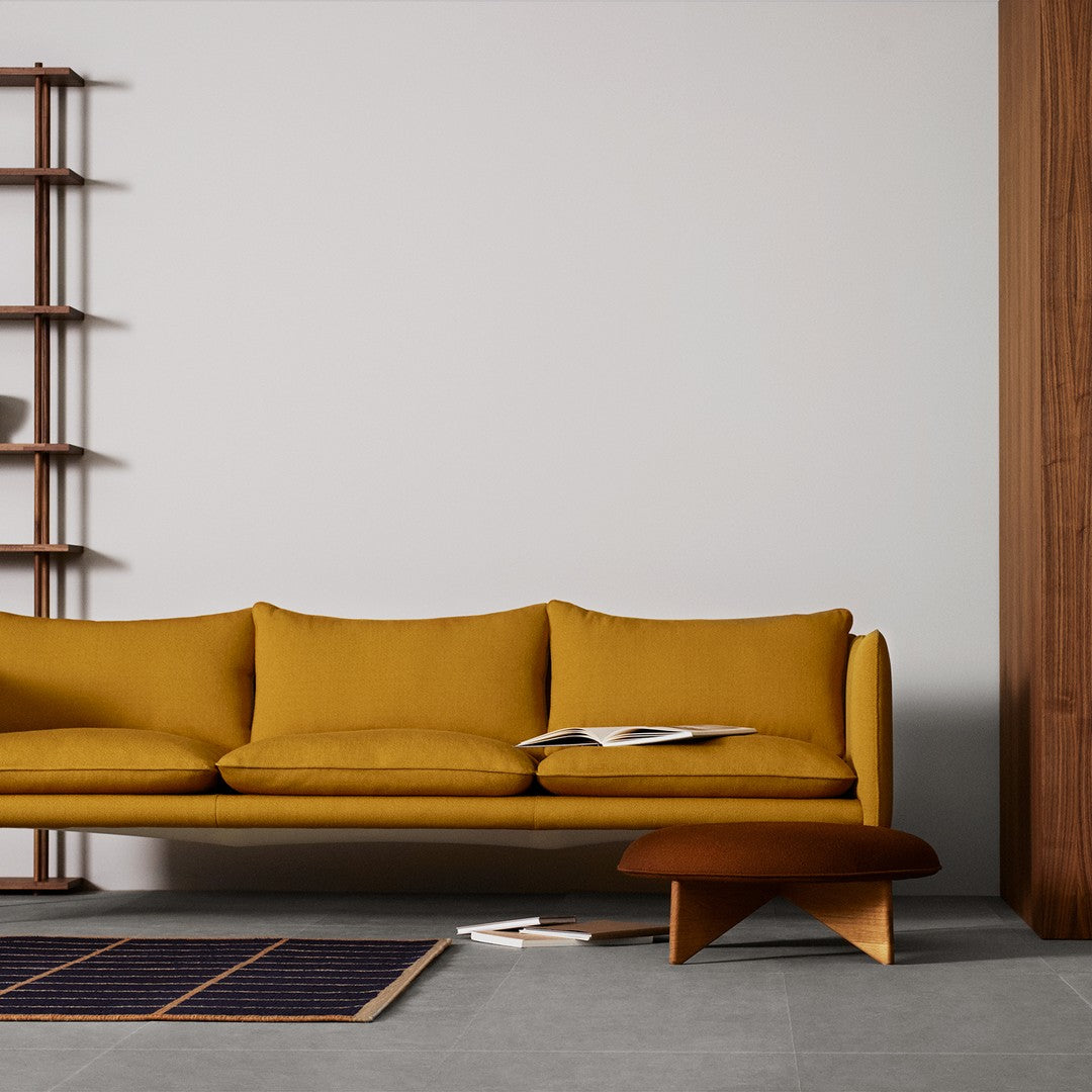 Stylish mustard yellow sofa with simple lines, complemented by a dark blue patterned rug and warm wood accents.