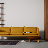 Stylish mustard yellow sofa with simple lines, complemented by a dark blue patterned rug and warm wood accents.