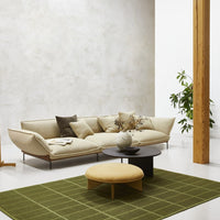 Beige sofa with neutral cushions, round yellow ottoman, and a green grid-pattern rug on a light floor.