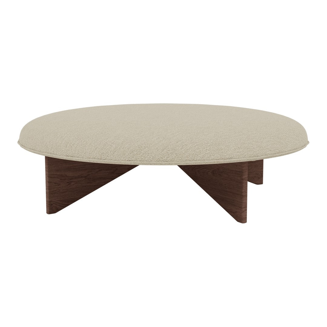 Round beige coffee table with textured surface, supported by dark wood legs, featuring a modern minimalist style.