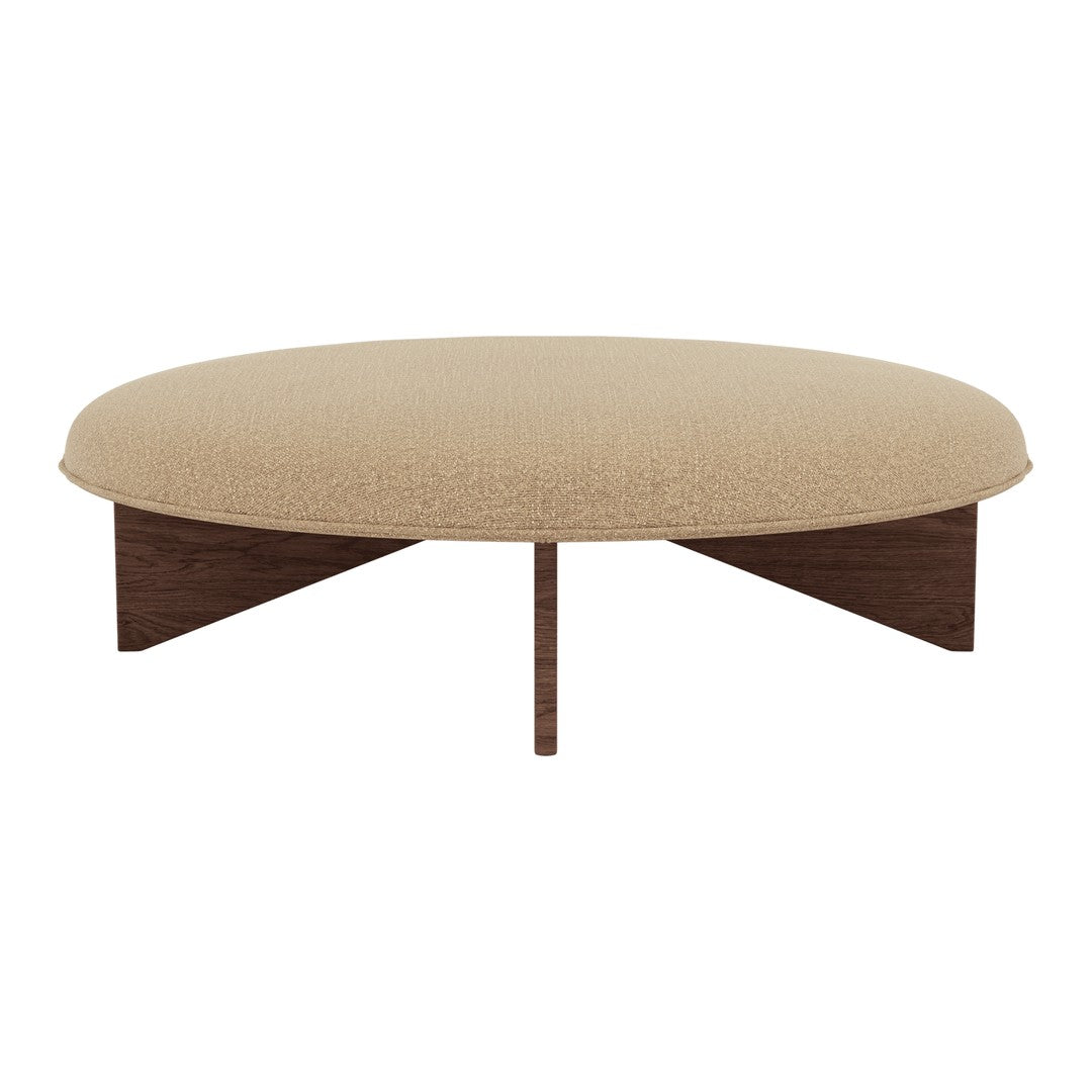 Beige round coffee table with a textured fabric top and modern wooden legs. Minimalist design with soft, neutral tones.