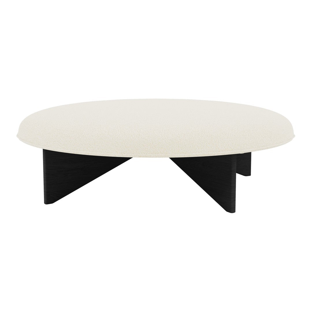 Round coffee table with a cream surface and black geometric legs, showcasing a modern design.