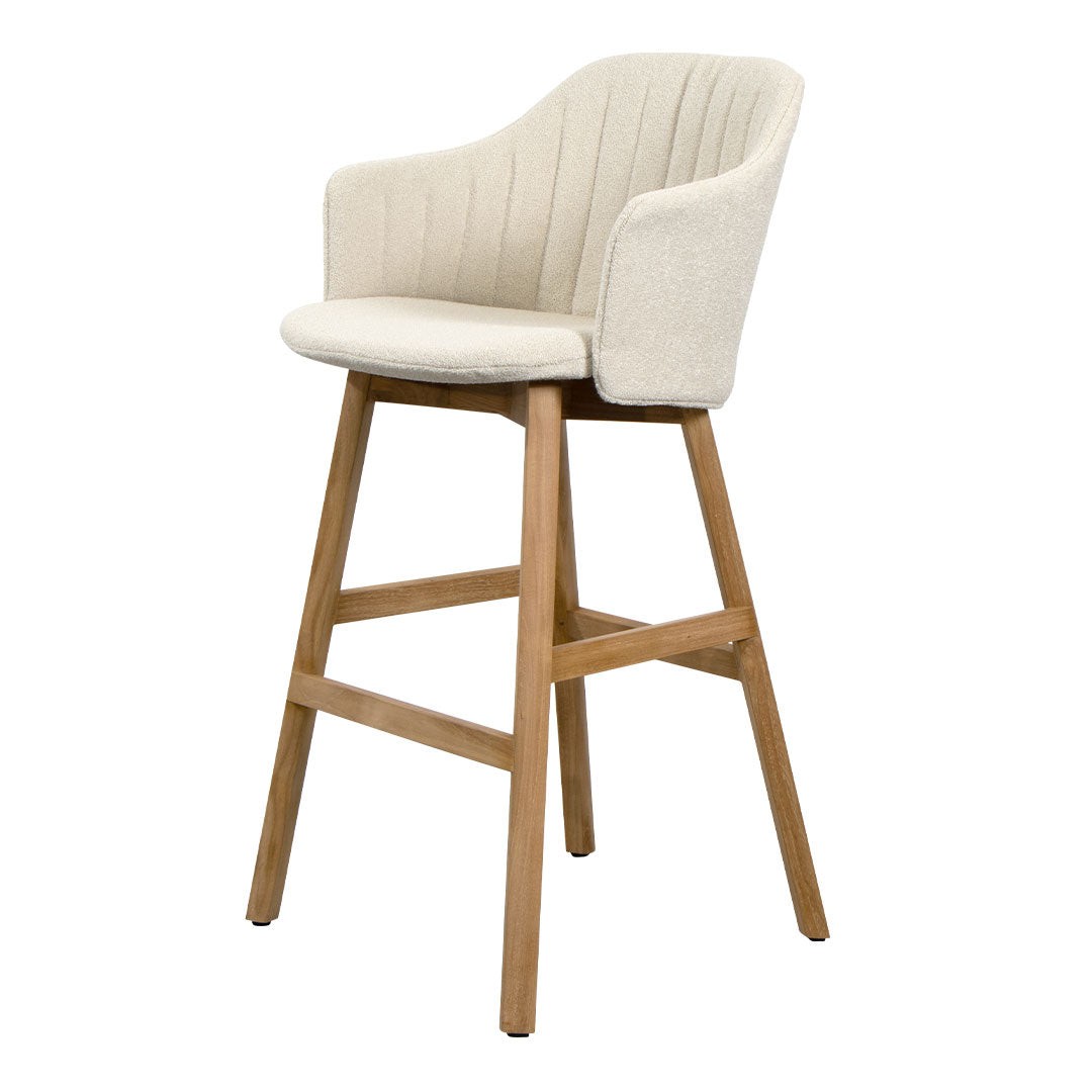 Cream upholstered bar stool with ribbed pattern and natural wood legs. Elegant and modern design for any space.