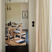 "Modern dining room featuring a black and white geometric rug paired with natural wood furniture and neutral decor."