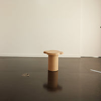 Light beige round stool with smooth, minimalist design against a neutral backdrop. Ideal for modern decor.