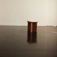 Minimalist stool in warm beige and rich brown tones, featuring a smooth, curved surface and simple design.
