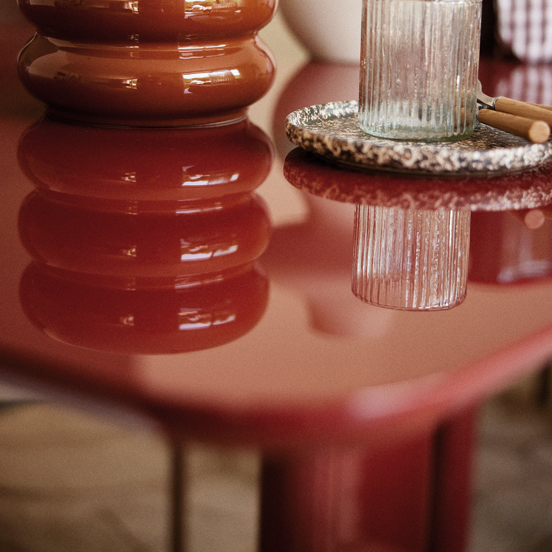 Glossy deep red table with a smooth finish, elegant patterns, and reflections. Perfect for modern decor.