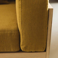 Mustard yellow sofa cushion with a textured fabric and clean wooden frame. Modern, stylish, and inviting design.
