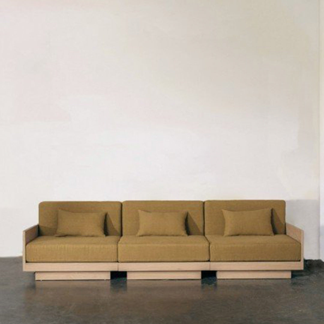 Stylish sofa with a minimalist design in warm brown fabric against a neutral background.