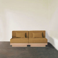 Modern two-seater sofa in warm mustard yellow with a simple, textured pattern and light wood base.