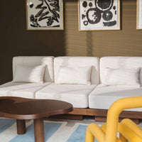 White modern sofa on a blue and cream geometric rug, contrasted by a brown wall and yellow accent furniture.