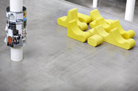 Bright yellow modern seating in playful shapes on a concrete floor, showcasing vibrant color and unique design.