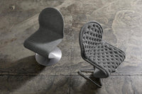 Modern grey upholstered chairs with smooth and tufted textures, set against a rustic concrete backdrop.
