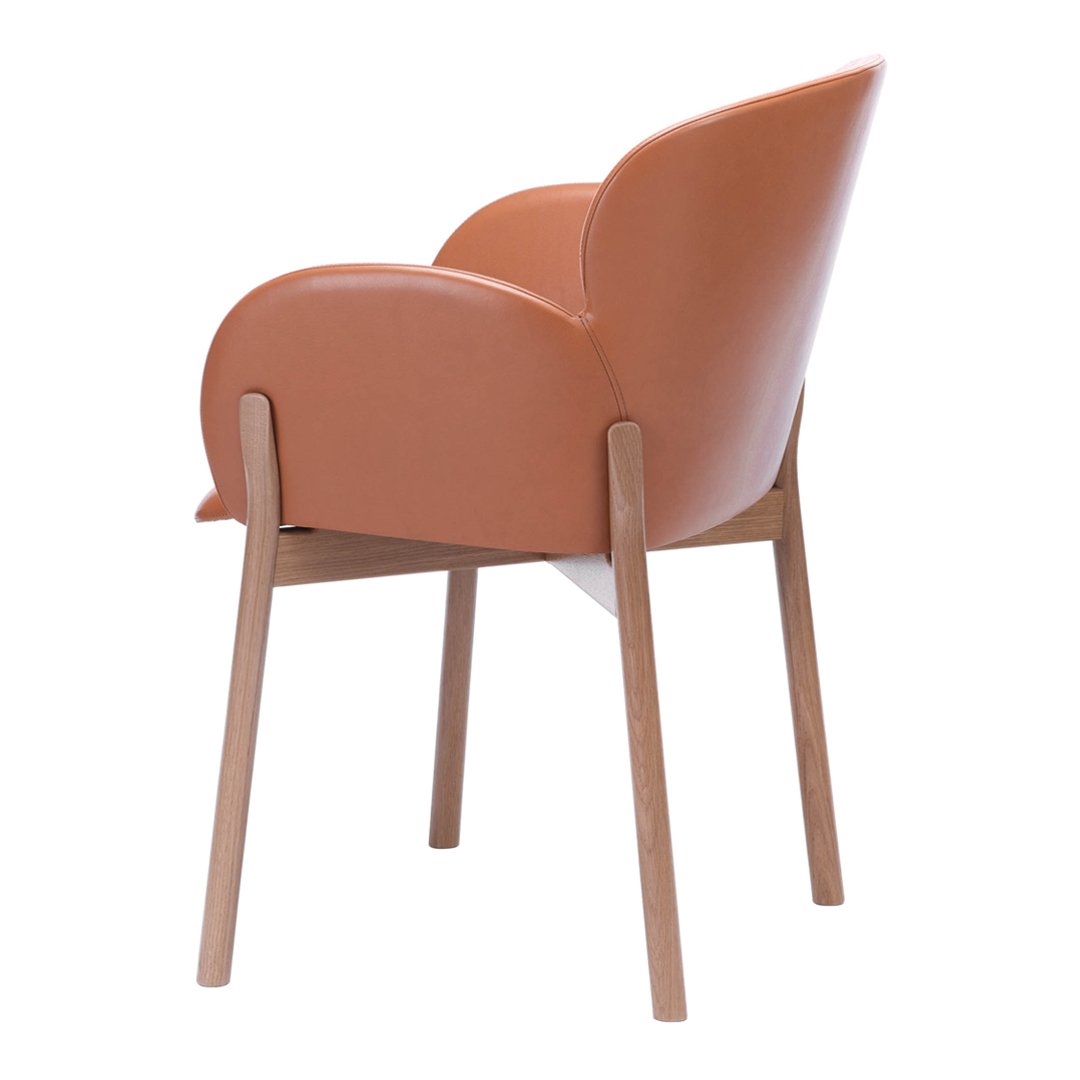 Elegant terracotta armchair with smooth, curved upholstery and natural wood legs, perfect for modern decor.