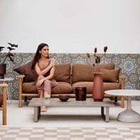 "Brown sofa with patterned backdrop in blue and orange, complemented by earthy-toned decorative vases."