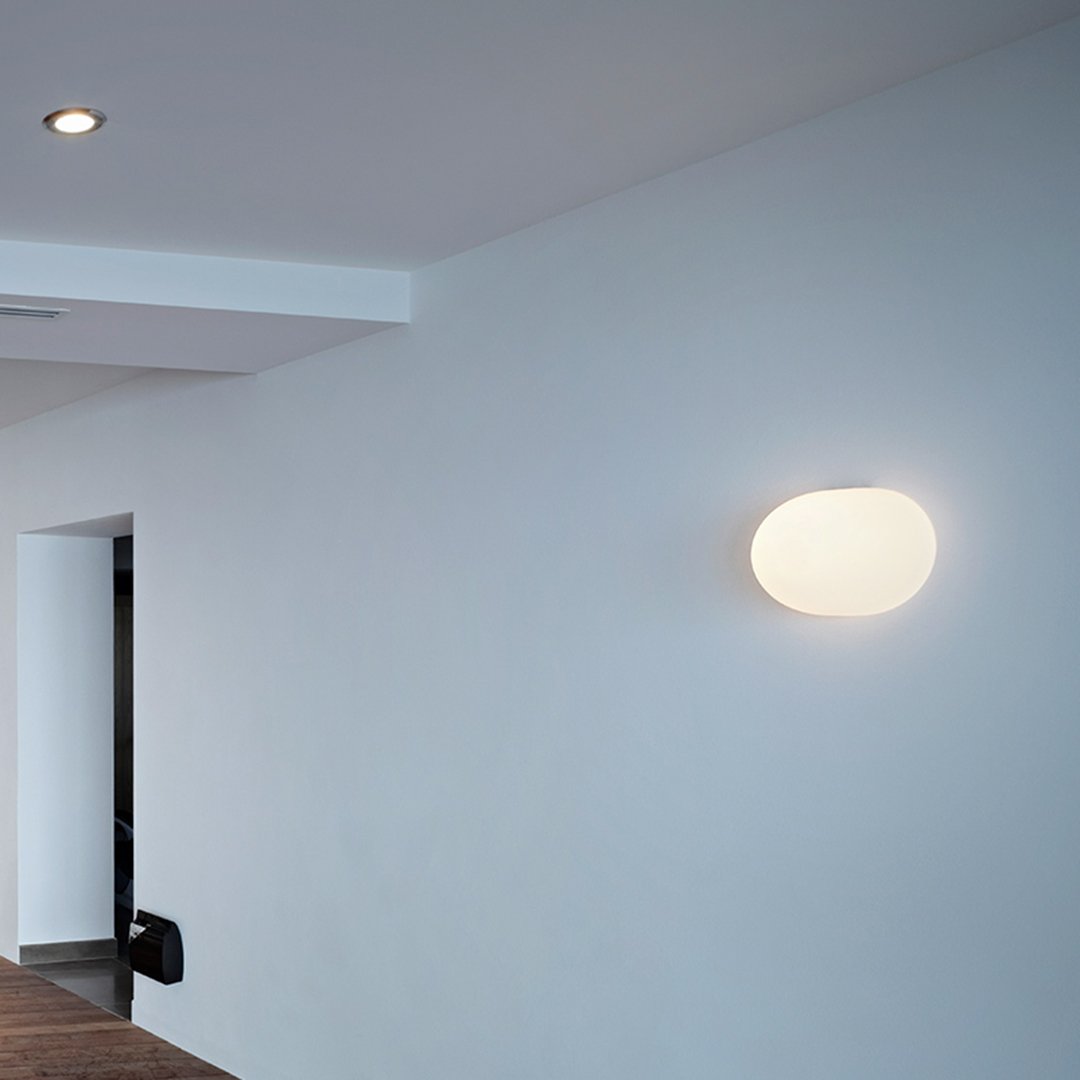 White oval wall light on a minimalist white background, providing soft illumination and clean design lines.