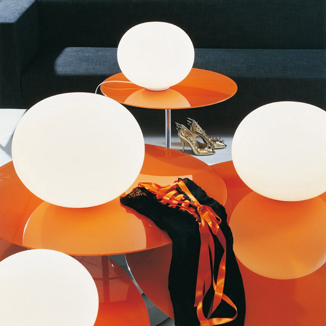 Modern orange tables with white globe lamps and a black fabric, creating a vibrant and stylish contrast.