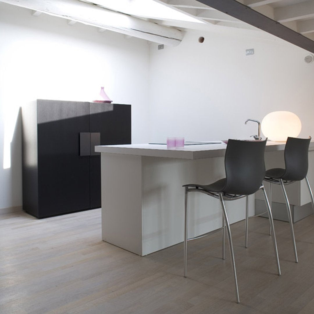 Modern kitchen featuring a sleek white island, black cabinetry, and minimalist design accents in soft pastel colors.