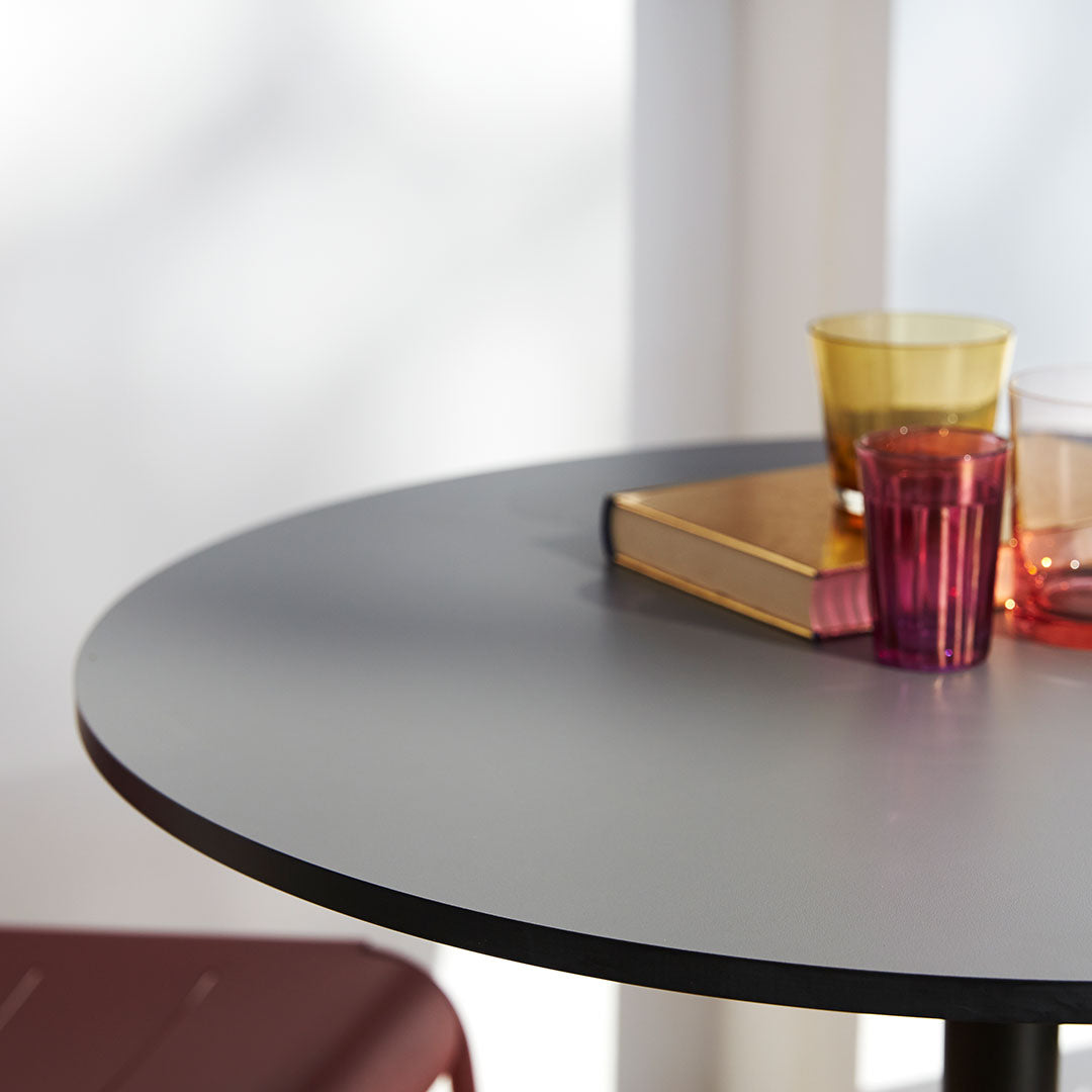 Round gray table with colorful glassware in yellow, orange, and pink, styled with a gold book.