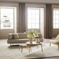 Light beige sofa with neutral accents, soft gray rug, and earthy wooden furniture, complemented by soft natural lighting.
