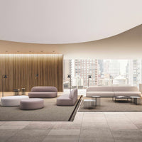 Modern lounge with soft pink, white, and gray seating; textured light wood accents and smooth concrete flooring.
