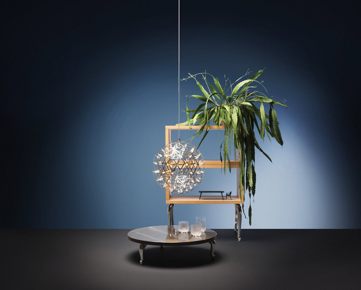 Elegant wooden shelf with a geometric light fixture, vibrant green plant, and sleek black table against a deep blue backdrop.
