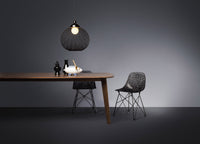 Black pendant light and patterned chairs contrast with a warm wooden table on a sleek gray backdrop.