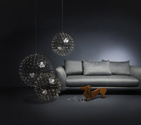 Sleek gray sofa with modern black and metallic hanging light fixtures against a dark background. Sophisticated and stylish design.