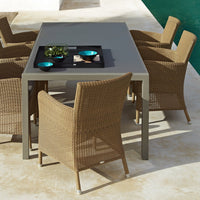 Brown wicker chairs around a gray table, accented with turquoise and black bowls on a light stone surface.